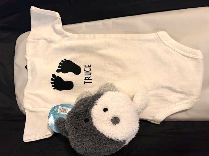 White baby onesie with footprints and a custom name
